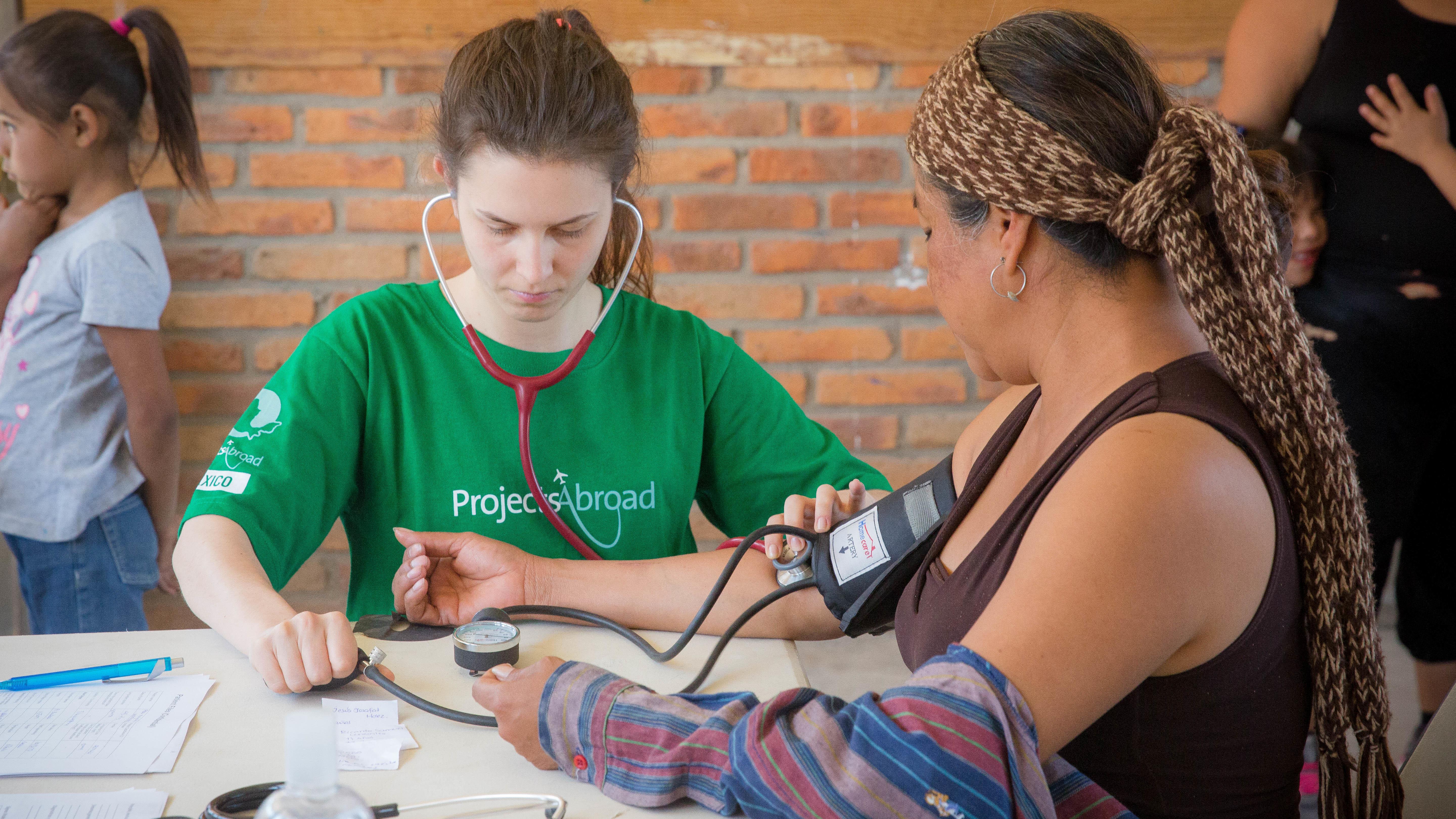 On the Public Health Internship for teenagers in Mexico, an intern checks a woman’s blood pressure levels. At her Projects Abroad Public Health placement for teenagers in Mexico, an intern checks a woman’s vital signs.